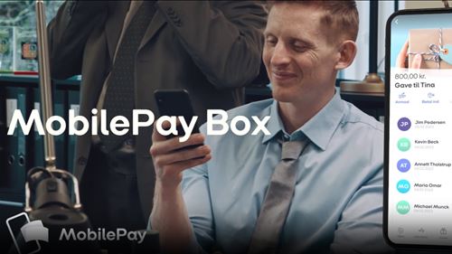 En mand kigger på sin telefon, ved siden af er en afbidling af en smartphone med MobilePay Box app'en